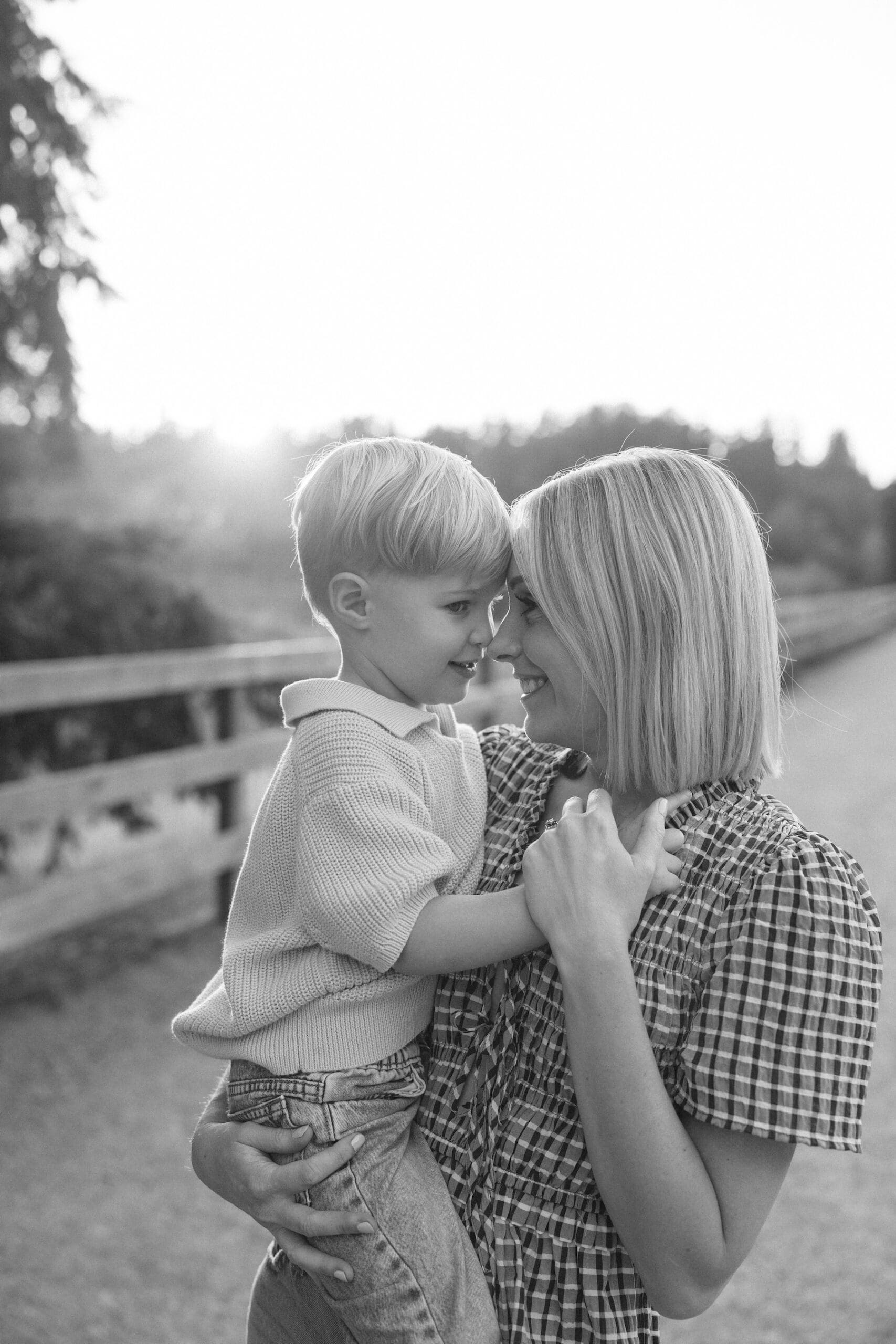 black and white photo of mother touching foreheads with toddler son
