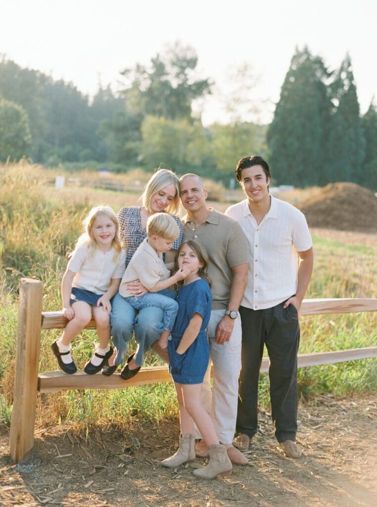 family of five poses on fence at marymoor park for family portrait