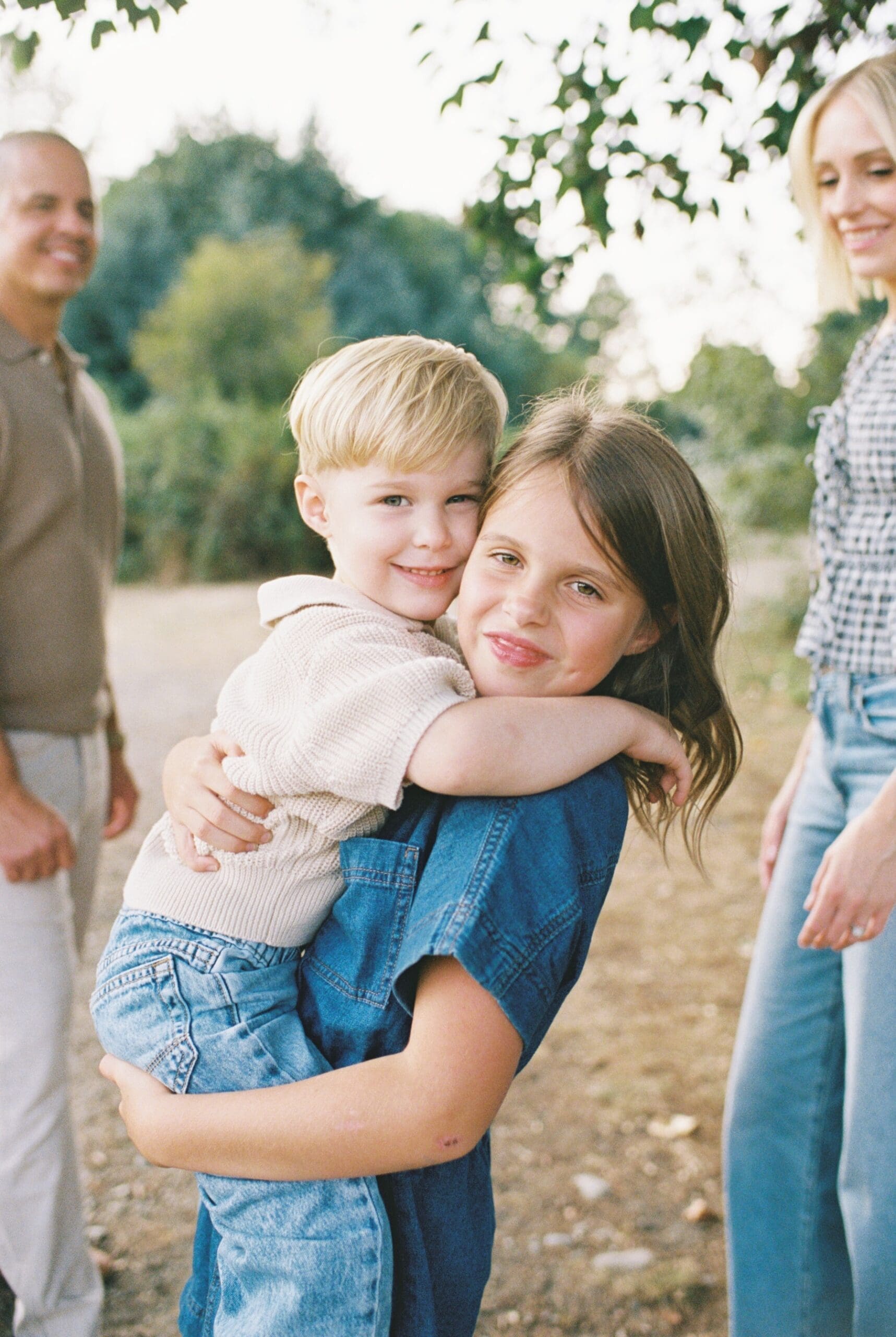 sister holding little brother smiling at camera 