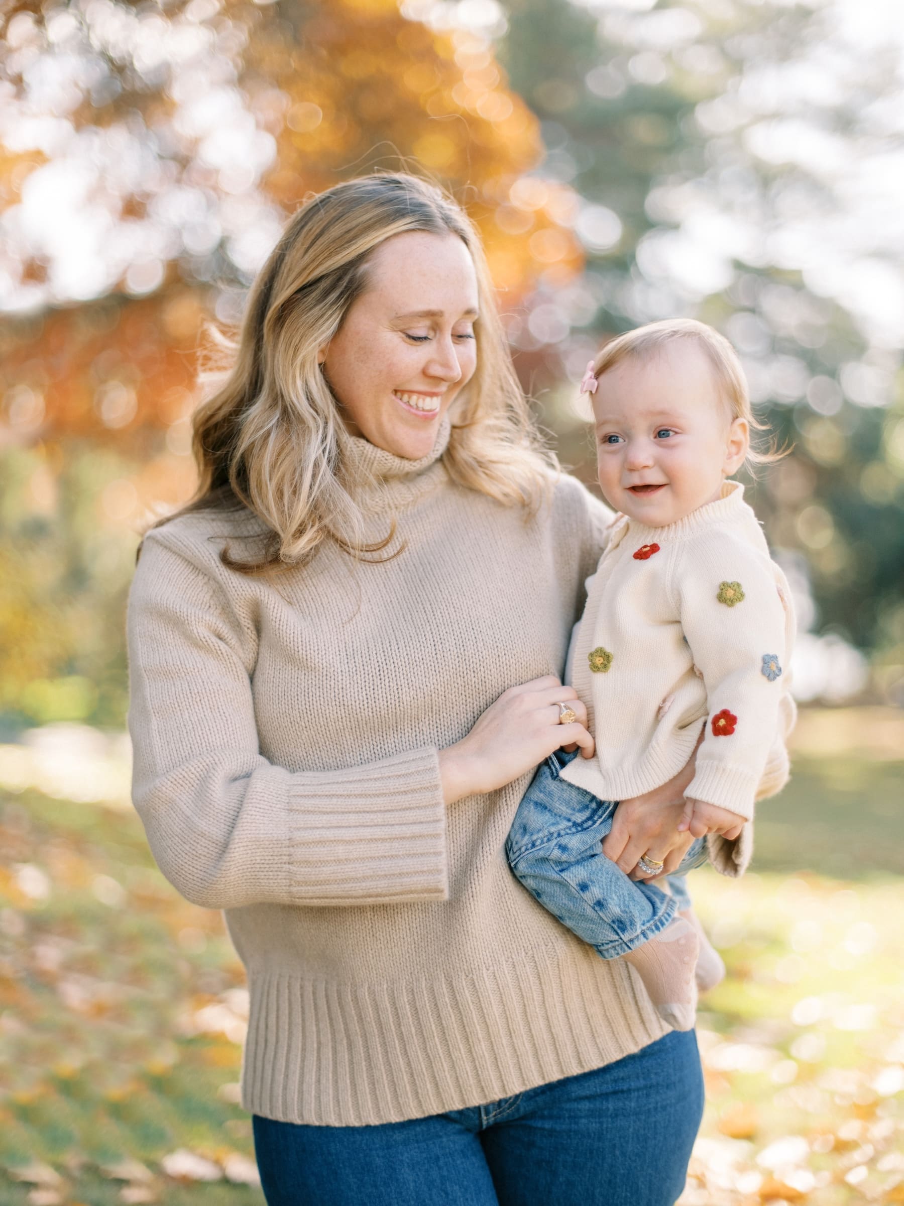 Seattle Fall Mini Session: Mother and baby daughter smiling in a park with autumn foliage. Family photo.