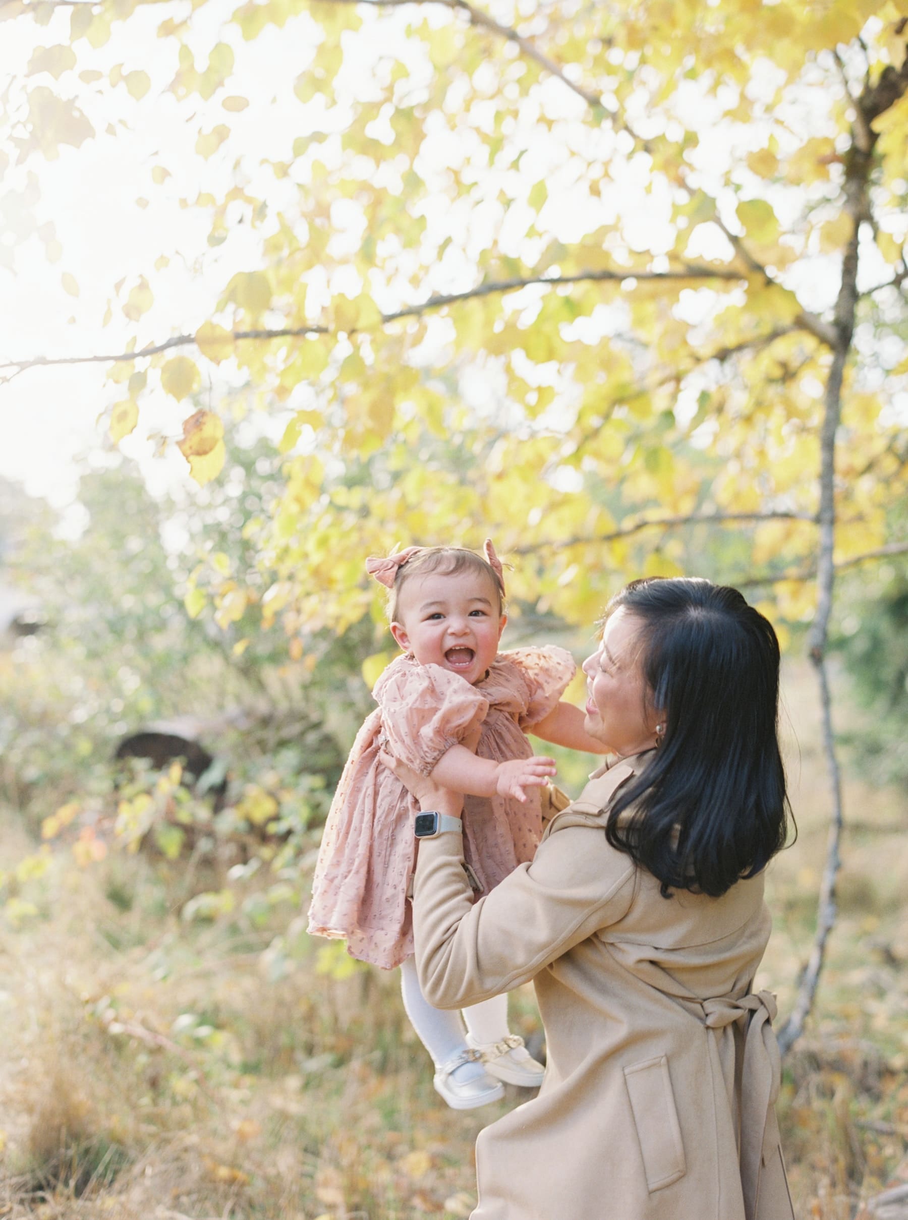 Kirkland family photography: Mother holding baby girl in Juanita Bay Park, fall foliage. Happy family portrait.