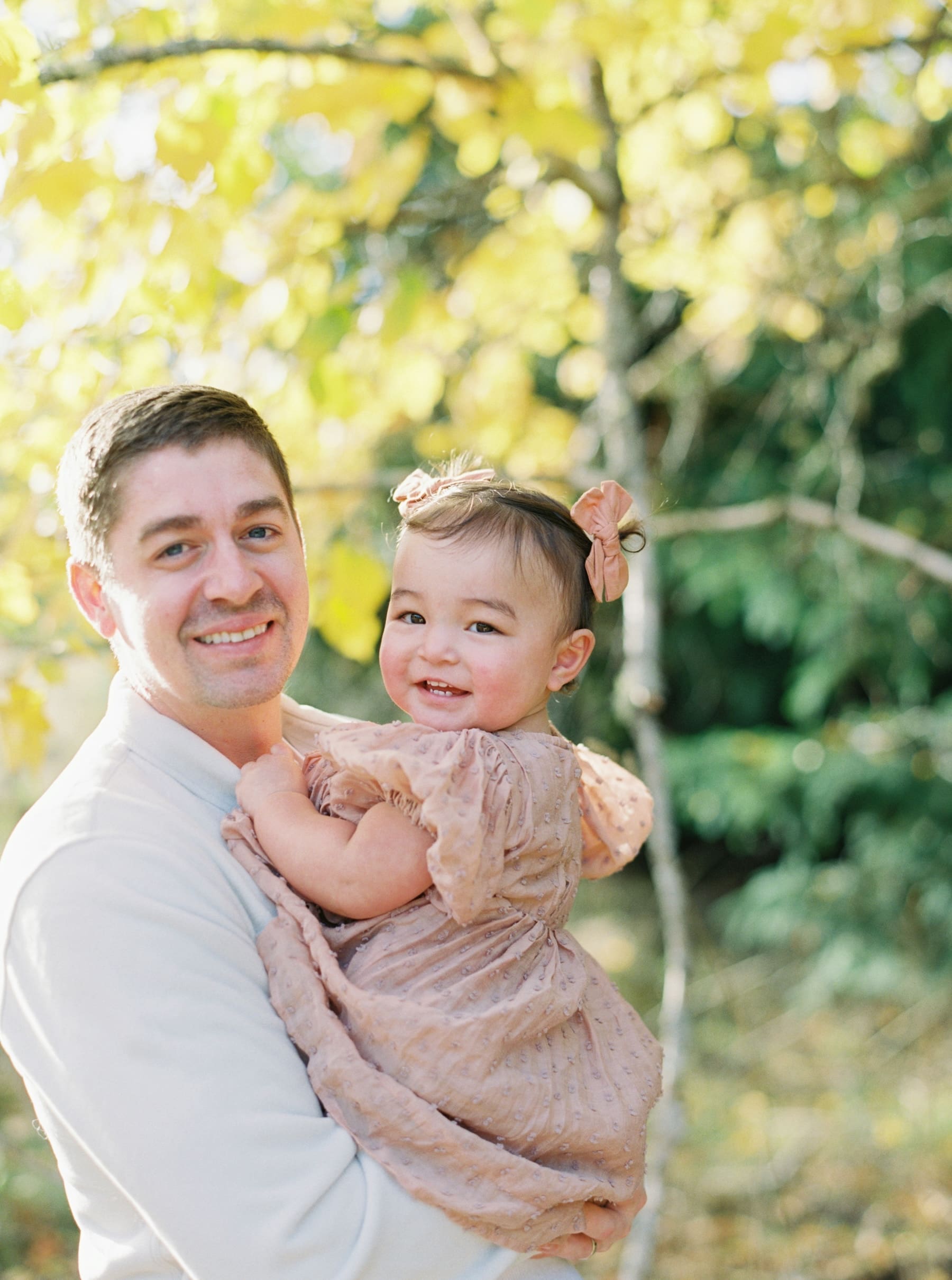 Kirkland family photography: Dad holding baby at Juanita Bay Park, smiling in natural light. Beautiful family portrait.