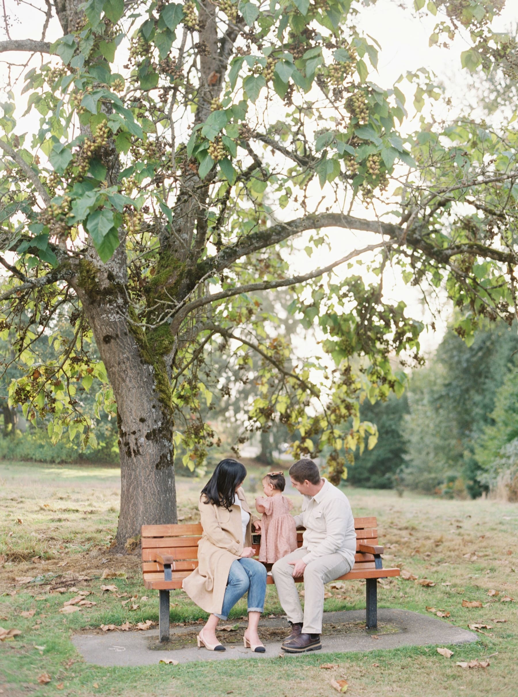 Kirkland family photography session at Juanita Bay Park. Parents kissing while holding their baby girl.