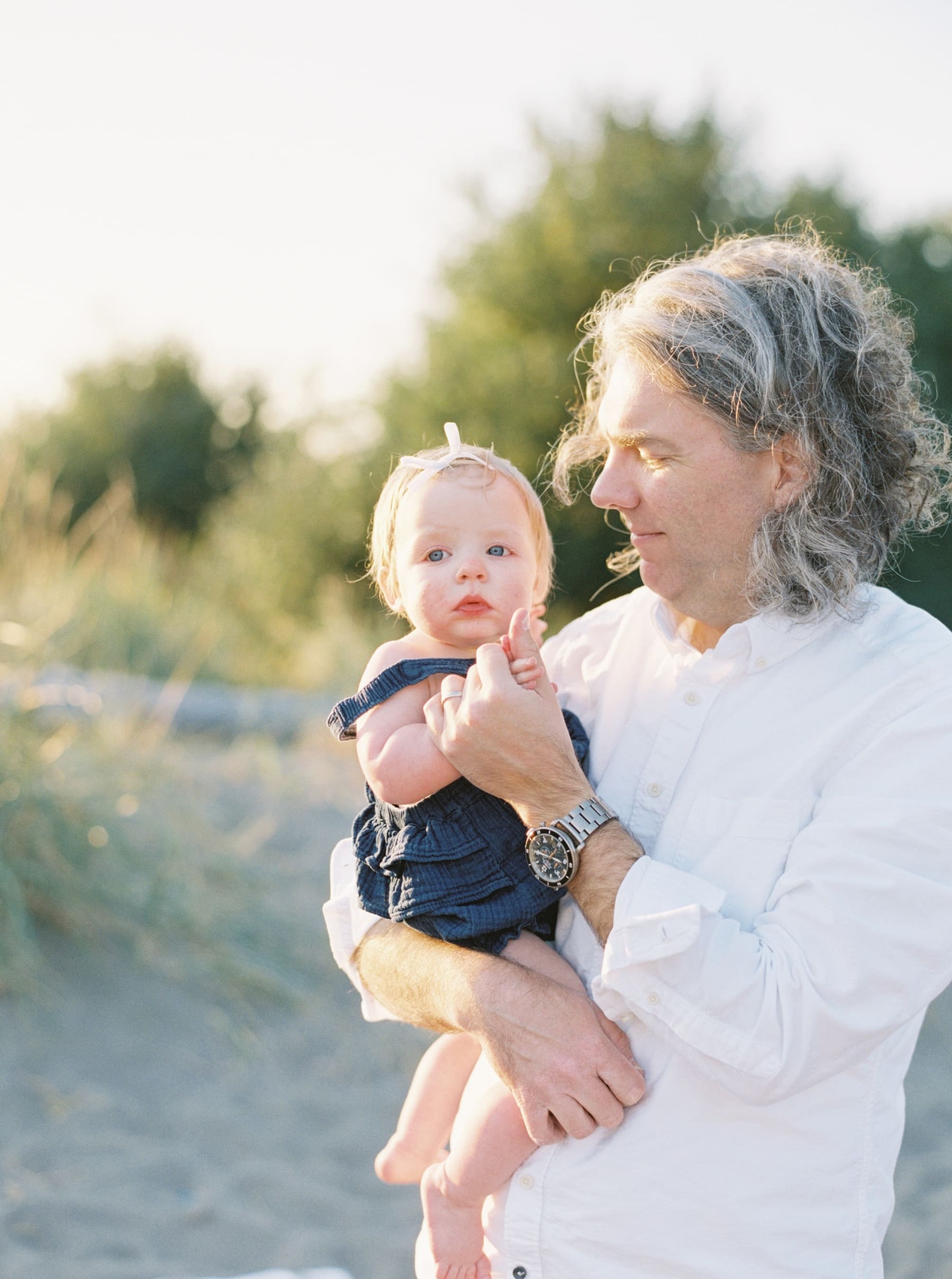 dad holding baby daughter at the beach