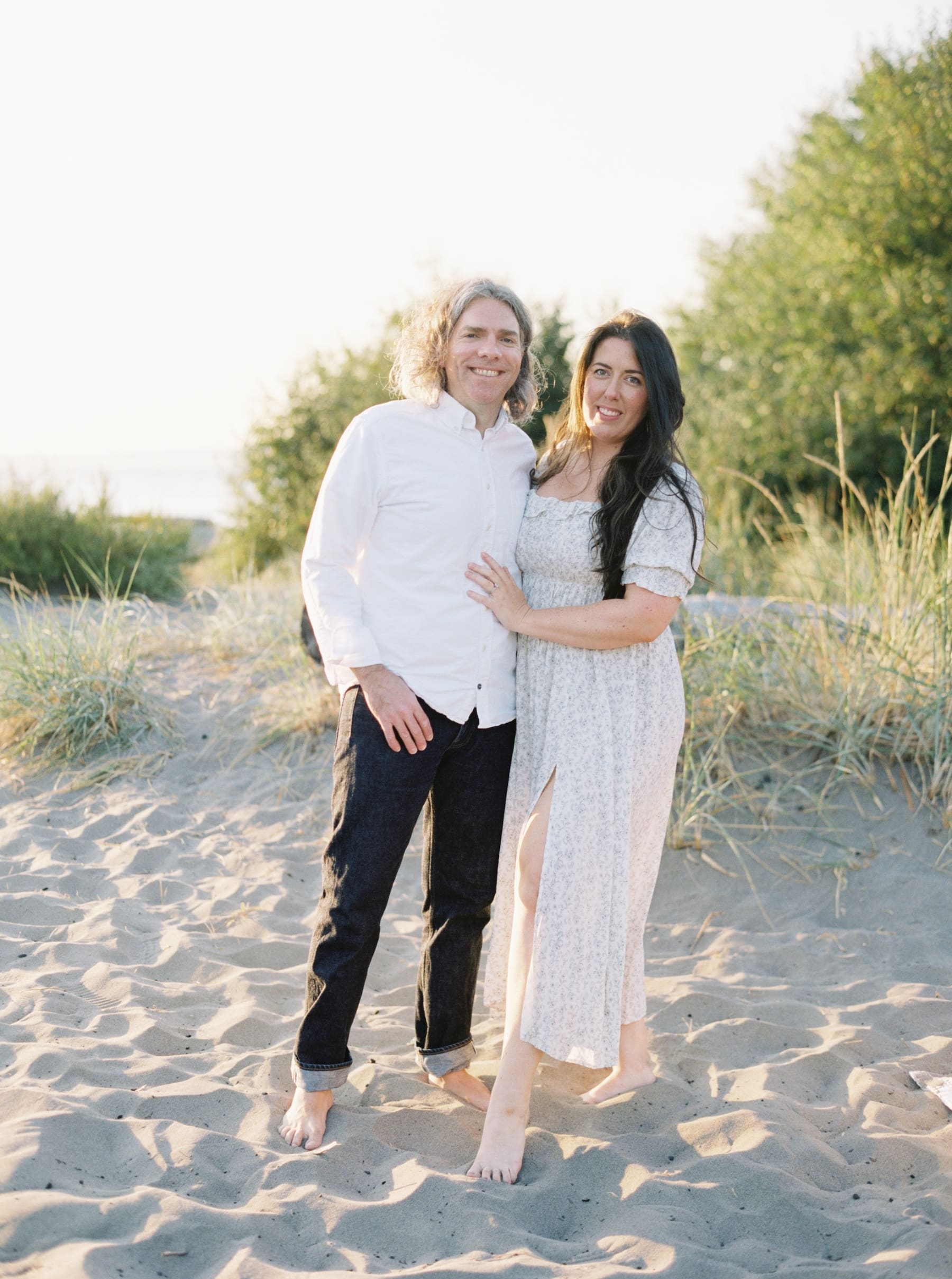 couple standing in sand at the beach posing for portrait