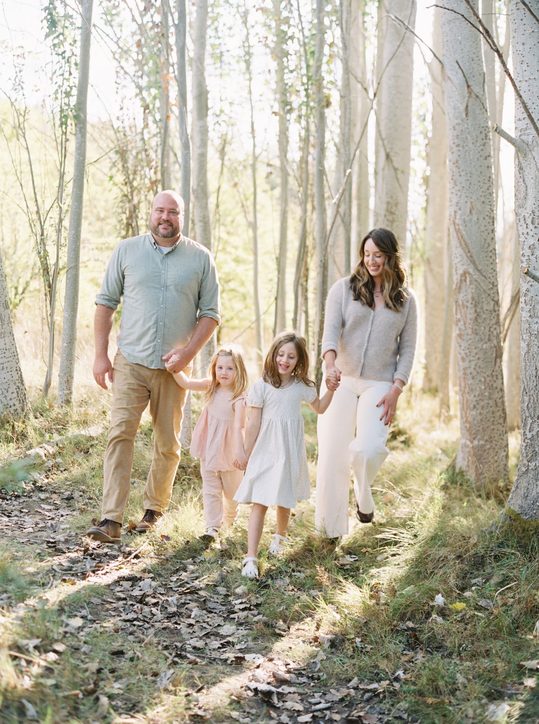 Seattle fall mini session: Family of four walks hand-in-hand through the woods, creating lasting memories.
