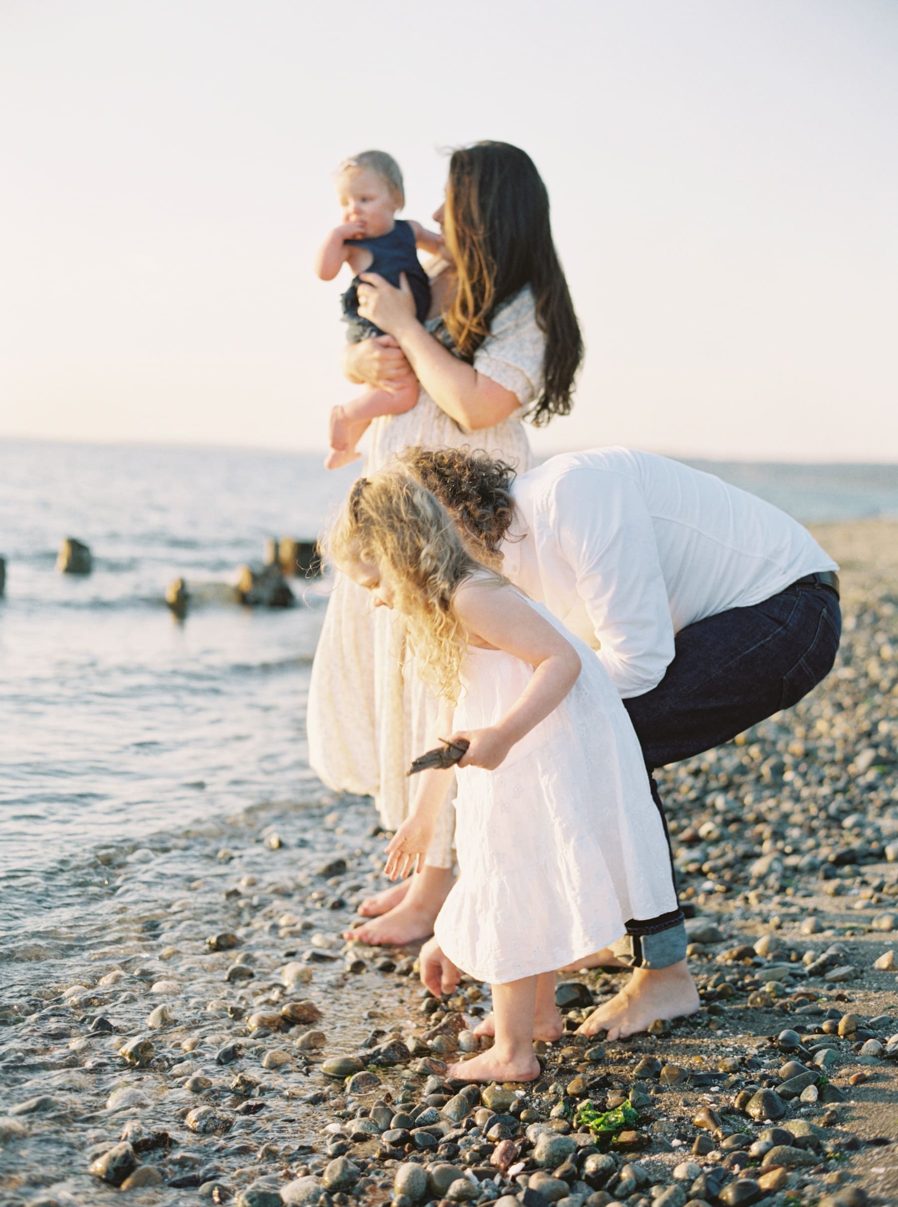 family photos on the beach at golden gardens candidly throwing rocks in water