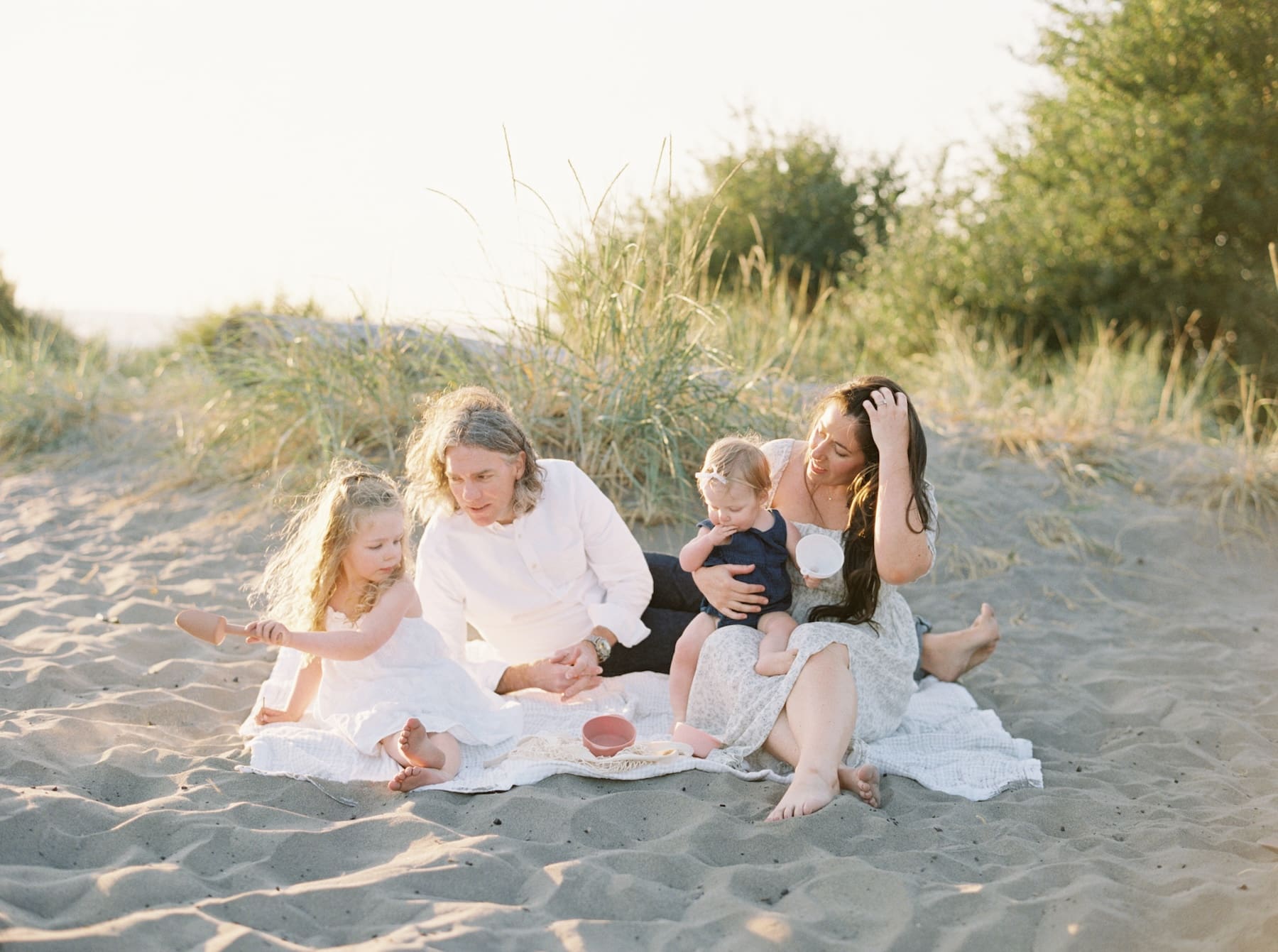 family of four on sandy beach in white outfits