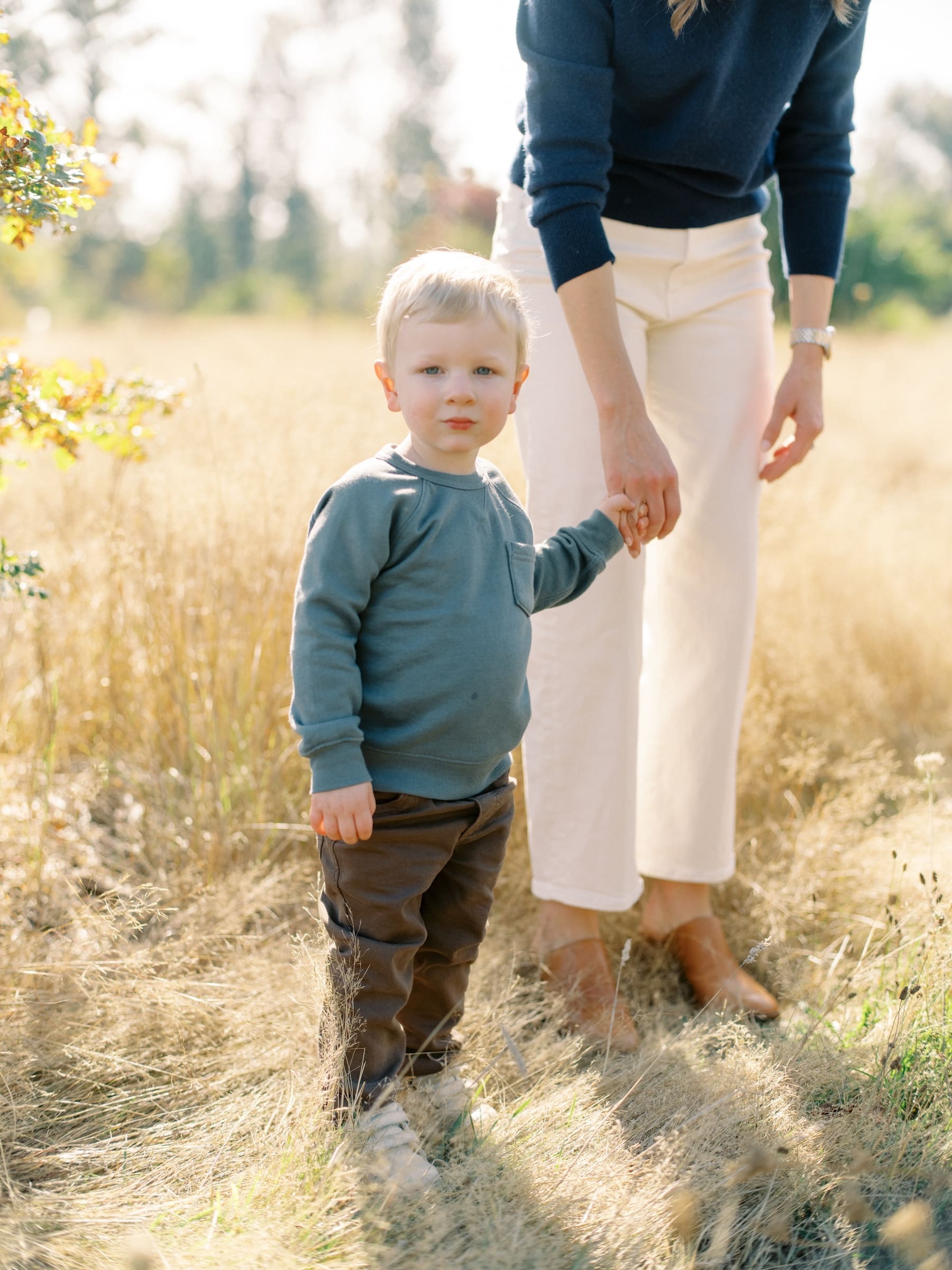 Seattle Fall Mini Session: A cute child holds hands with their mother in a sunny field.