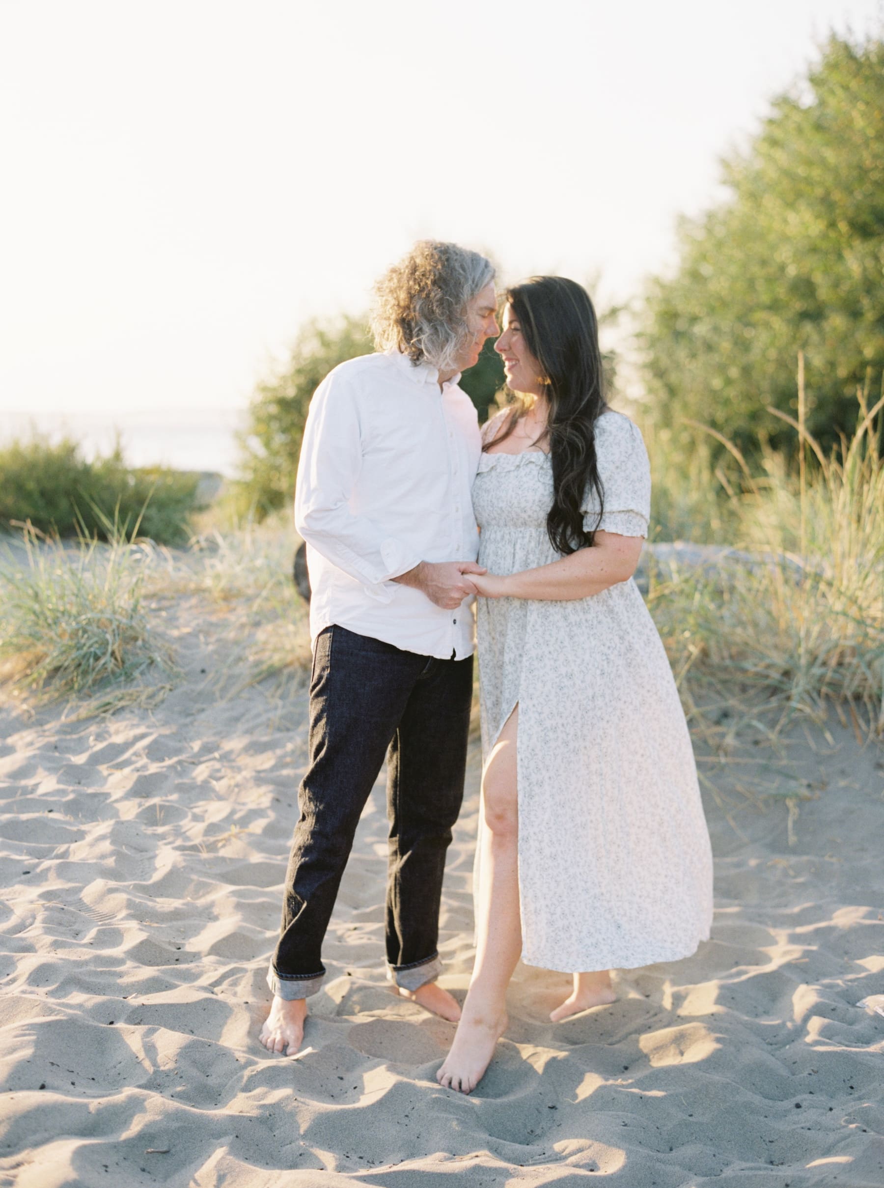 couple touching foreheads while standing on sandy beach in seattle