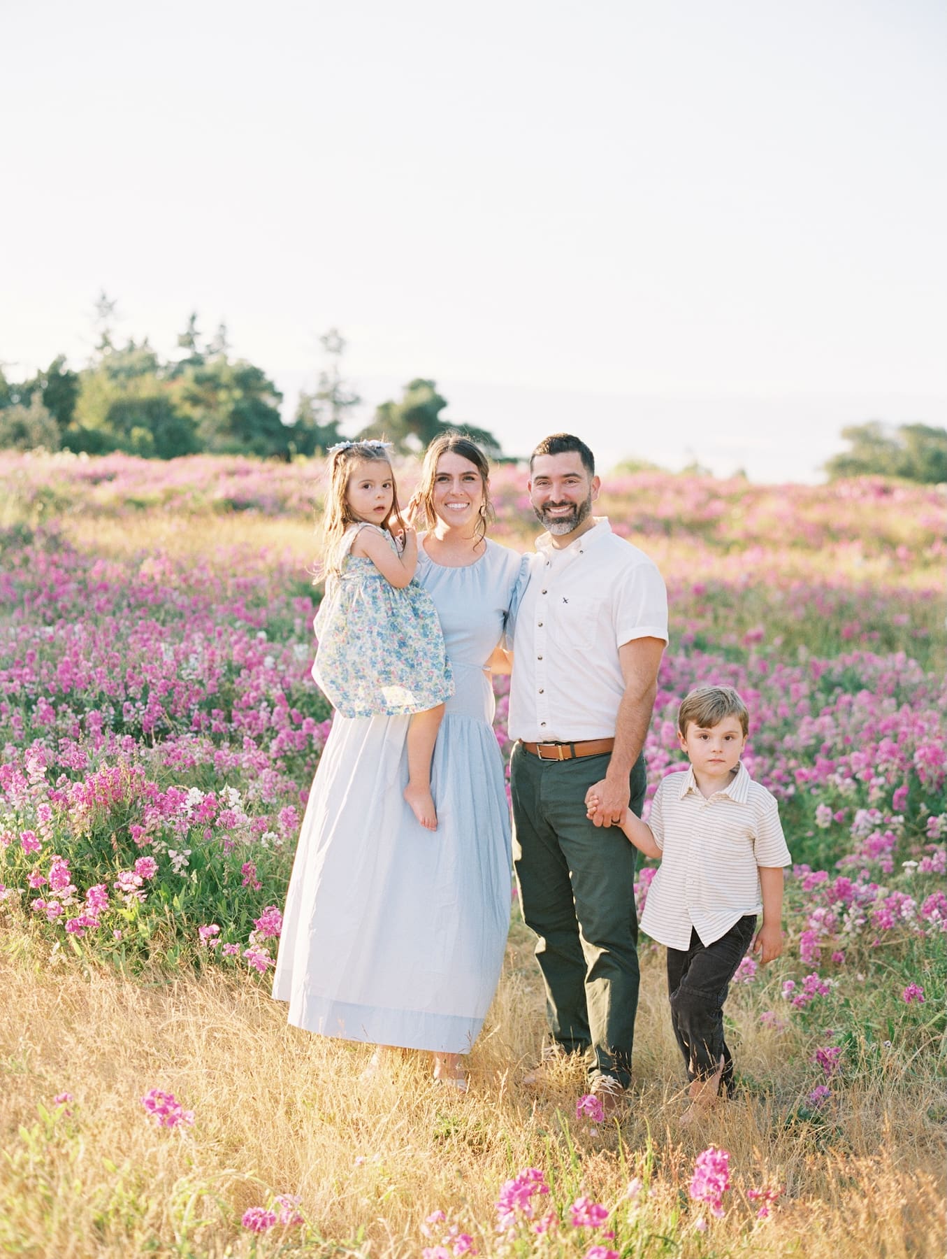 Family poses for a photo amongst pink wild flowers at Seattles Discovery Park